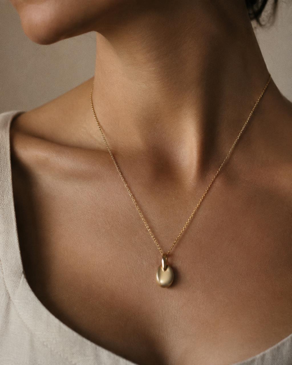 Gold pendant worn at the collarbone